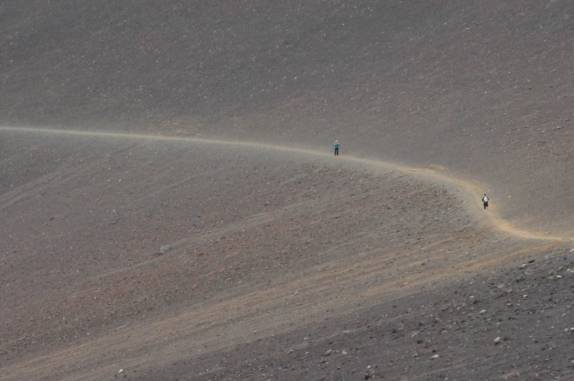 Minúsculos e insignificantes na paisagem, turistas percorrem trilha que entra na cratera do vulcão Haleakala, em  Maui, no Havaí